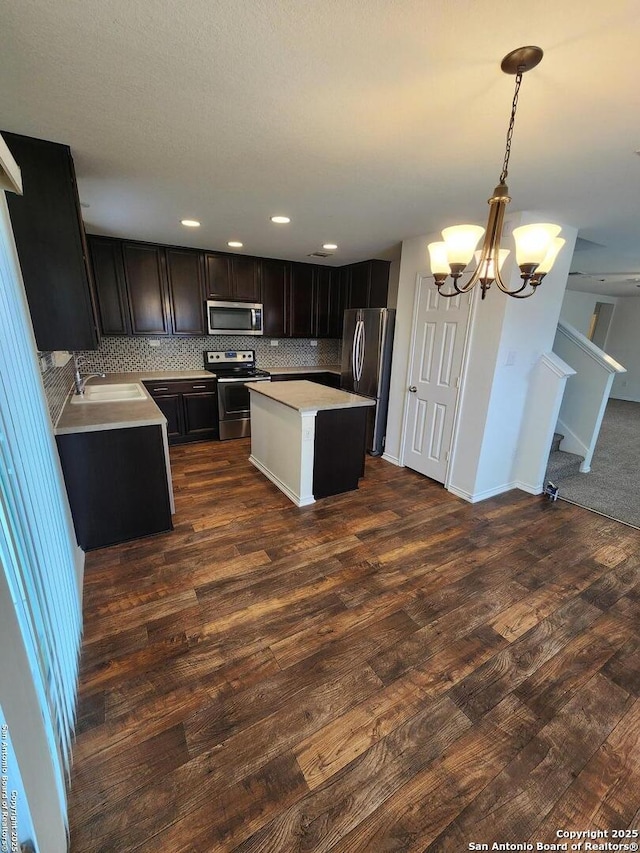 kitchen with a chandelier, stainless steel appliances, light countertops, dark wood finished floors, and backsplash