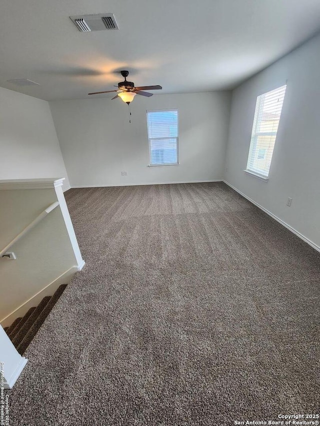 unfurnished living room with baseboards, a ceiling fan, visible vents, and carpet floors