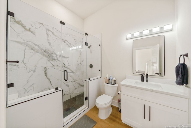 full bath featuring wood finished floors, toilet, vanity, and a marble finish shower