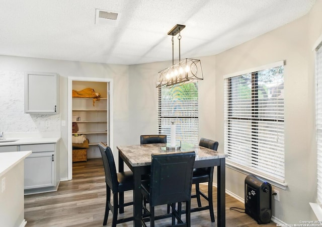 dining room featuring light wood finished floors, an inviting chandelier, and a textured ceiling