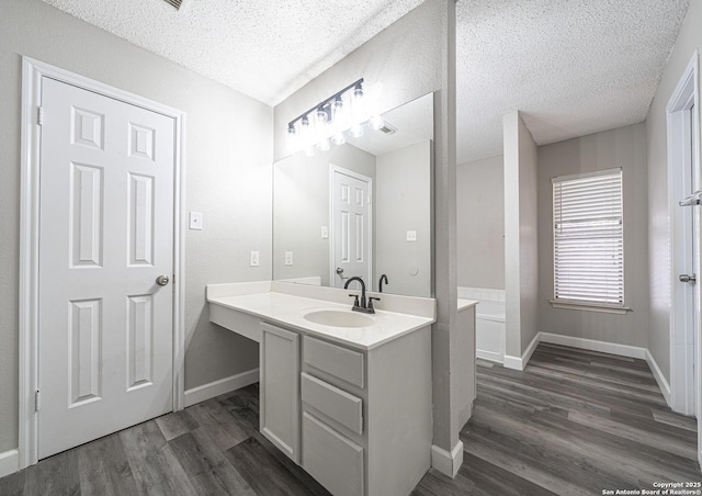 bathroom with baseboards, vanity, wood finished floors, and a textured ceiling