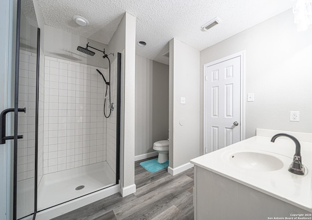 full bath featuring a sink, toilet, a stall shower, visible vents, and wood finished floors