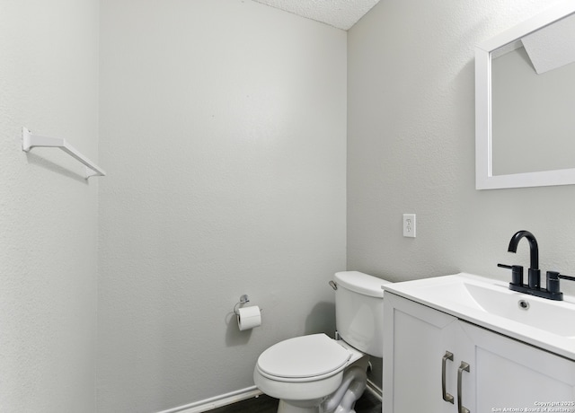 bathroom with toilet, vanity, and a textured ceiling