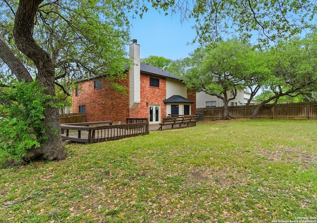 back of house featuring a lawn, french doors, a fenced backyard, a wooden deck, and brick siding