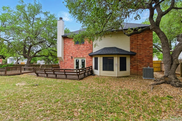 back of property with brick siding, a yard, french doors, and central AC