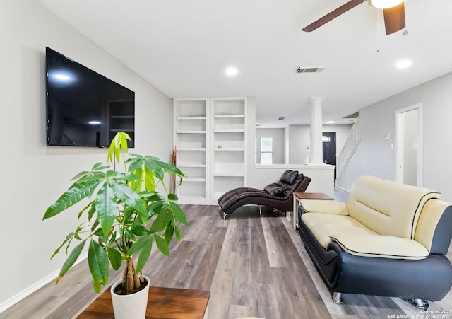 living room featuring ornate columns, wood finished floors, visible vents, baseboards, and ceiling fan