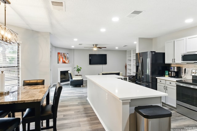 kitchen with a center island, recessed lighting, light wood-style floors, ceiling fan with notable chandelier, and appliances with stainless steel finishes