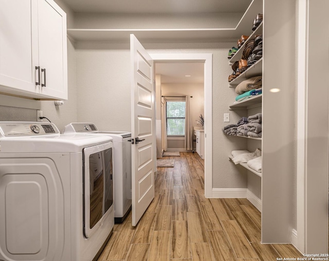177 E Short Meadow Dr, Lytle, TX 78052 - clothes washing area featuring washing machine and dryer, baseboards, cabinet space, and light wood-style flooring