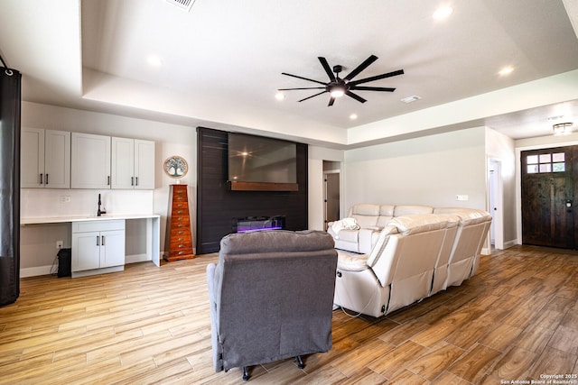 177 E Short Meadow Dr, Lytle, TX 78052 - living room featuring a tray ceiling, light wood-style flooring, ceiling fan, and recessed lighting