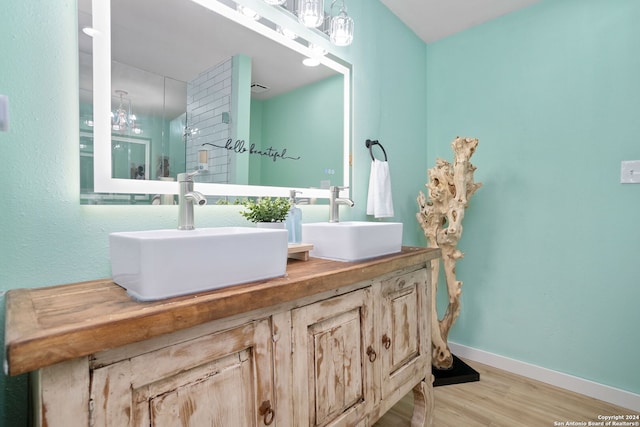 bathroom featuring baseboards, wood finished floors, a sink, and double vanity