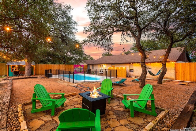 pool at dusk with a fenced in pool, a patio area, an outdoor fire pit, and fence