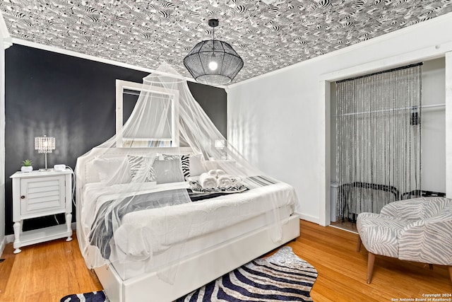 bedroom with wood finished floors, baseboards, and ornamental molding