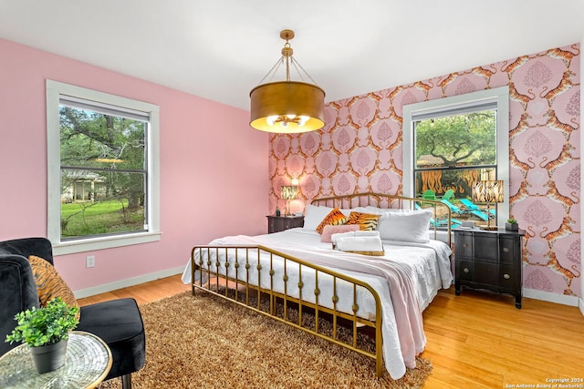 bedroom with wallpapered walls, light wood-style flooring, and baseboards