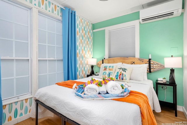 bedroom featuring baseboards, wood finished floors, and a wall mounted air conditioner