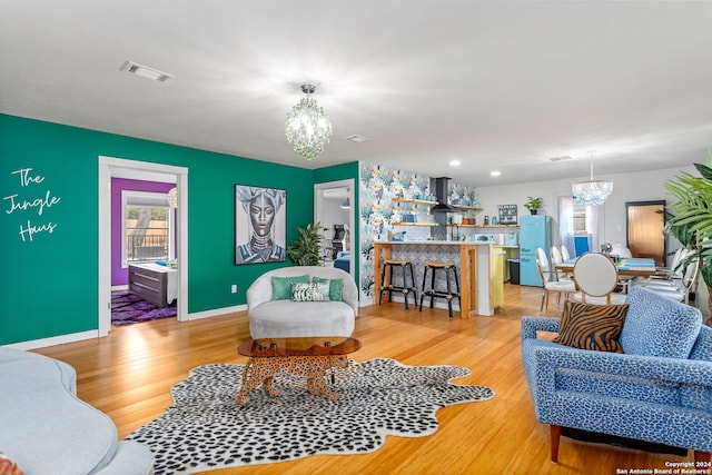 living room with baseboards, a notable chandelier, light wood finished floors, and visible vents