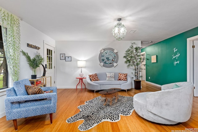 living area with baseboards, wood finished floors, and an inviting chandelier