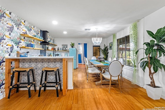 kitchen with a kitchen breakfast bar, an inviting chandelier, open shelves, visible vents, and light wood-style floors