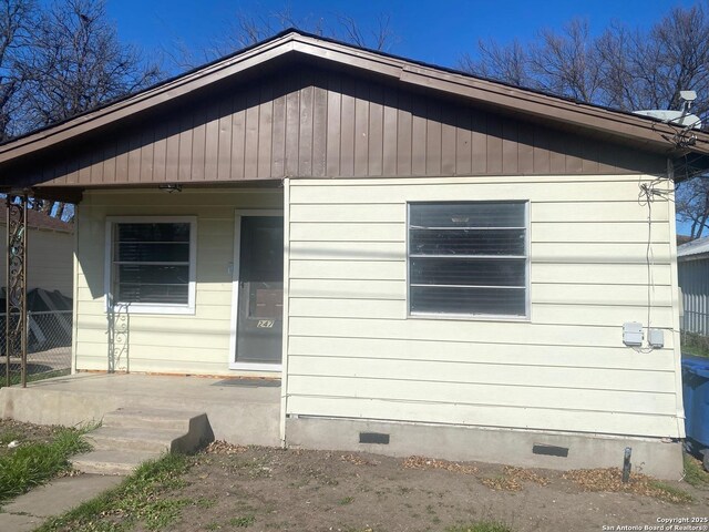 view of front of house with crawl space, a porch, and fence