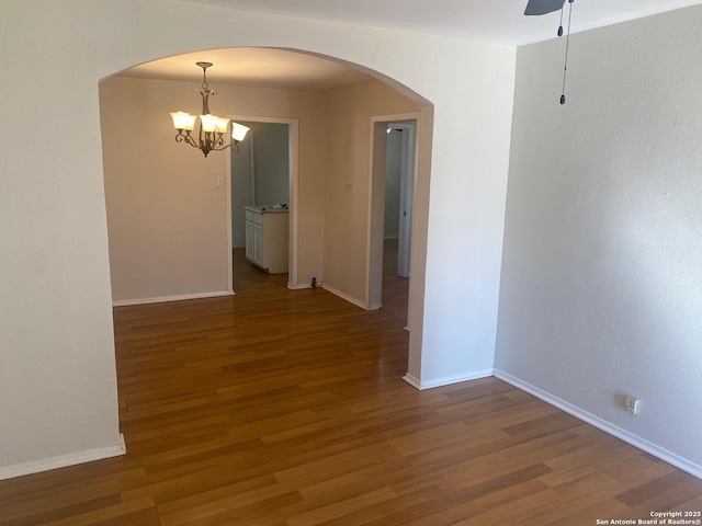 interior space featuring arched walkways, wood finished floors, and an inviting chandelier