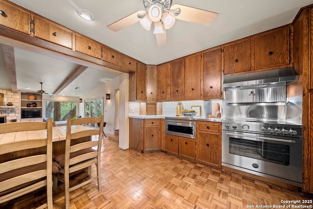 2802 State Highway 46, New Braunfels, TX 78132 - kitchen featuring a ceiling fan, stainless steel appliances, under cabinet range hood, brown cabinetry, and light countertops