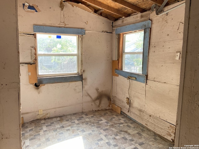 unfurnished room with light floors and lofted ceiling