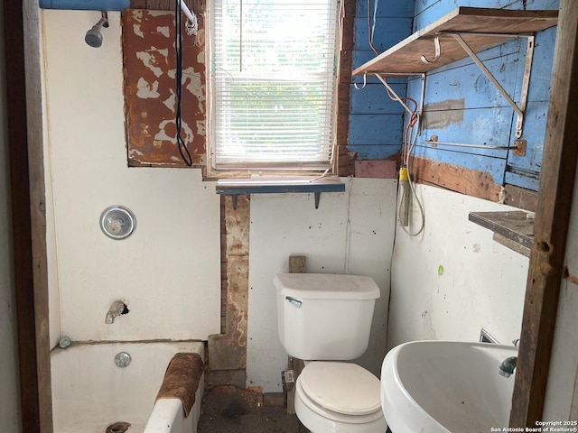 bathroom with toilet, a tub to relax in, and a sink