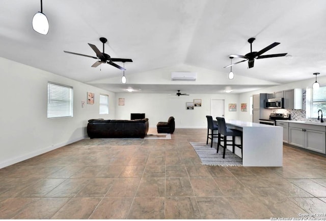 living room featuring a wall mounted AC, vaulted ceiling, baseboards, and ceiling fan