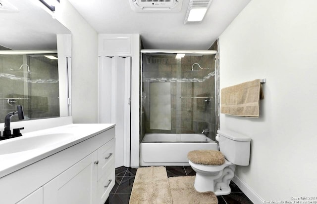 bathroom featuring a wall mounted air conditioner, vanity, bath / shower combo with glass door, toilet, and tile patterned flooring