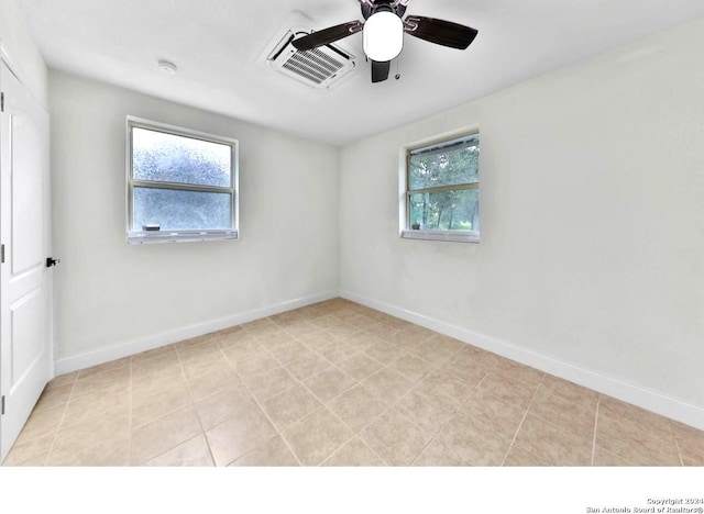empty room with baseboards, a ceiling fan, visible vents, and light tile patterned flooring