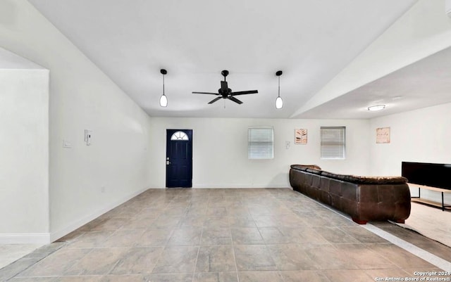 tiled living room featuring vaulted ceiling, a ceiling fan, and baseboards