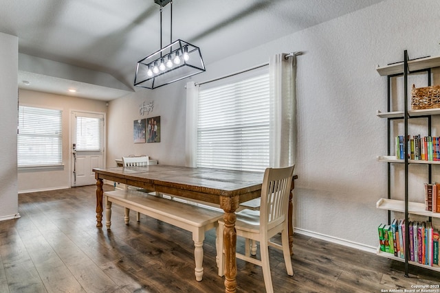 dining space with baseboards, a textured wall, wood finished floors, and an inviting chandelier