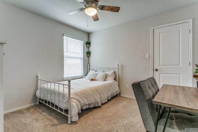 carpeted bedroom featuring baseboards, a ceiling fan, and a textured wall