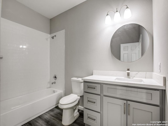 bathroom featuring toilet, vanity, wood finished floors, and shower / bathing tub combination