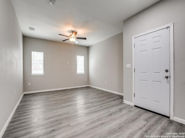 spare room with wood finished floors, a healthy amount of sunlight, and a ceiling fan