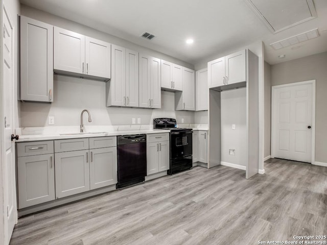 kitchen featuring a sink, black appliances, light countertops, gray cabinetry, and visible vents