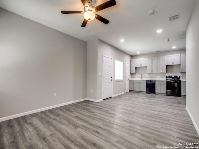 kitchen with black appliances, light wood-type flooring, light countertops, baseboards, and visible vents