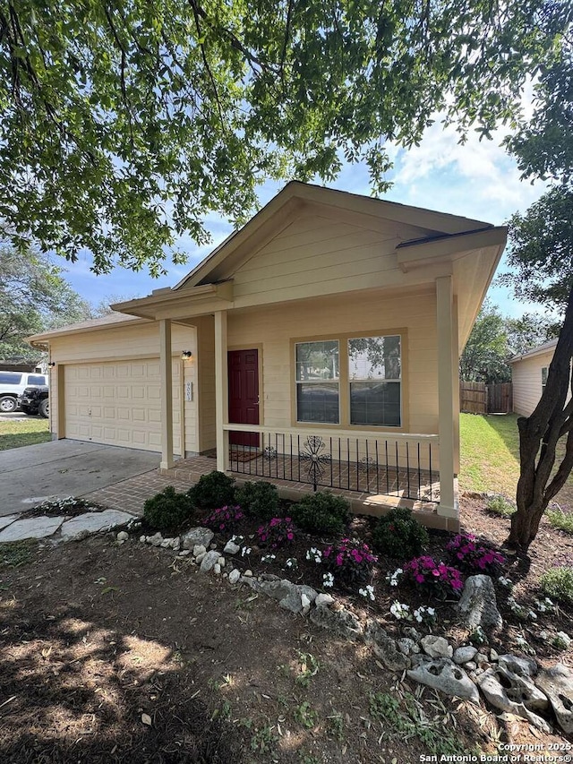 view of front of property featuring concrete driveway, fence, a garage, and covered porch