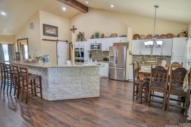 745 County Road 2645, Moore, TX 78057 - kitchen with decorative backsplash, visible vents, appliances with stainless steel finishes, and a barn door