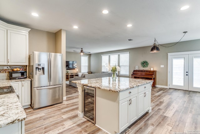 kitchen featuring light wood-style flooring, stainless steel fridge, white cabinetry, a ceiling fan, and beverage cooler