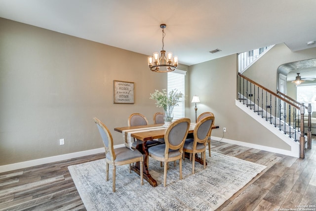 dining room featuring wood finished floors, visible vents, baseboards, and stairway