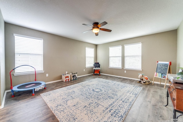 recreation room featuring ceiling fan, baseboards, and wood finished floors