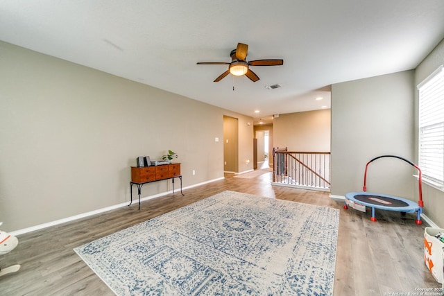interior space featuring wood finished floors, plenty of natural light, ceiling fan, baseboards, and visible vents