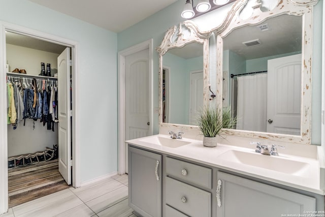 full bathroom with a walk in closet, a sink, visible vents, and double vanity