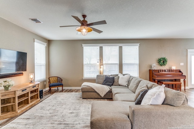 living room featuring a wealth of natural light, a ceiling fan, and wood finished floors