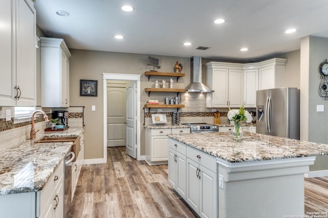 kitchen featuring light wood-style flooring, wall chimney exhaust hood, appliances with stainless steel finishes, and visible vents