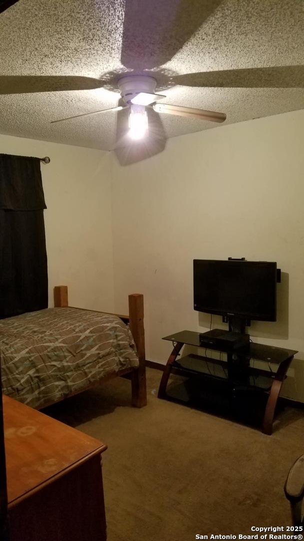 bedroom featuring carpet, a textured ceiling, and a ceiling fan