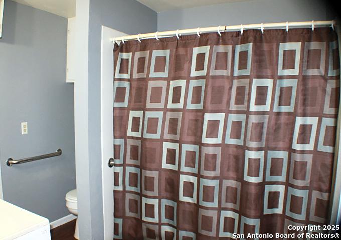 13444 Interstate 35, Moore, TX 78057 - full bath with wood finished floors, toilet, vanity, baseboards, and a shower with shower curtain