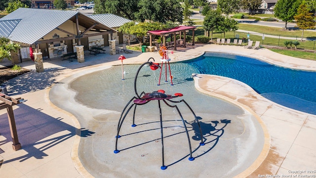 community pool featuring a water play area, fence, and a patio