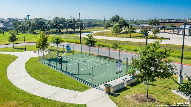 view of basketball court featuring community basketball court, fence, and a lawn