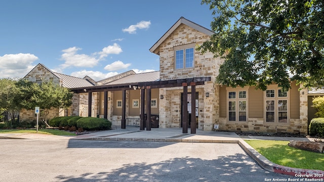 view of front facade featuring a standing seam roof, metal roof, and stone siding
